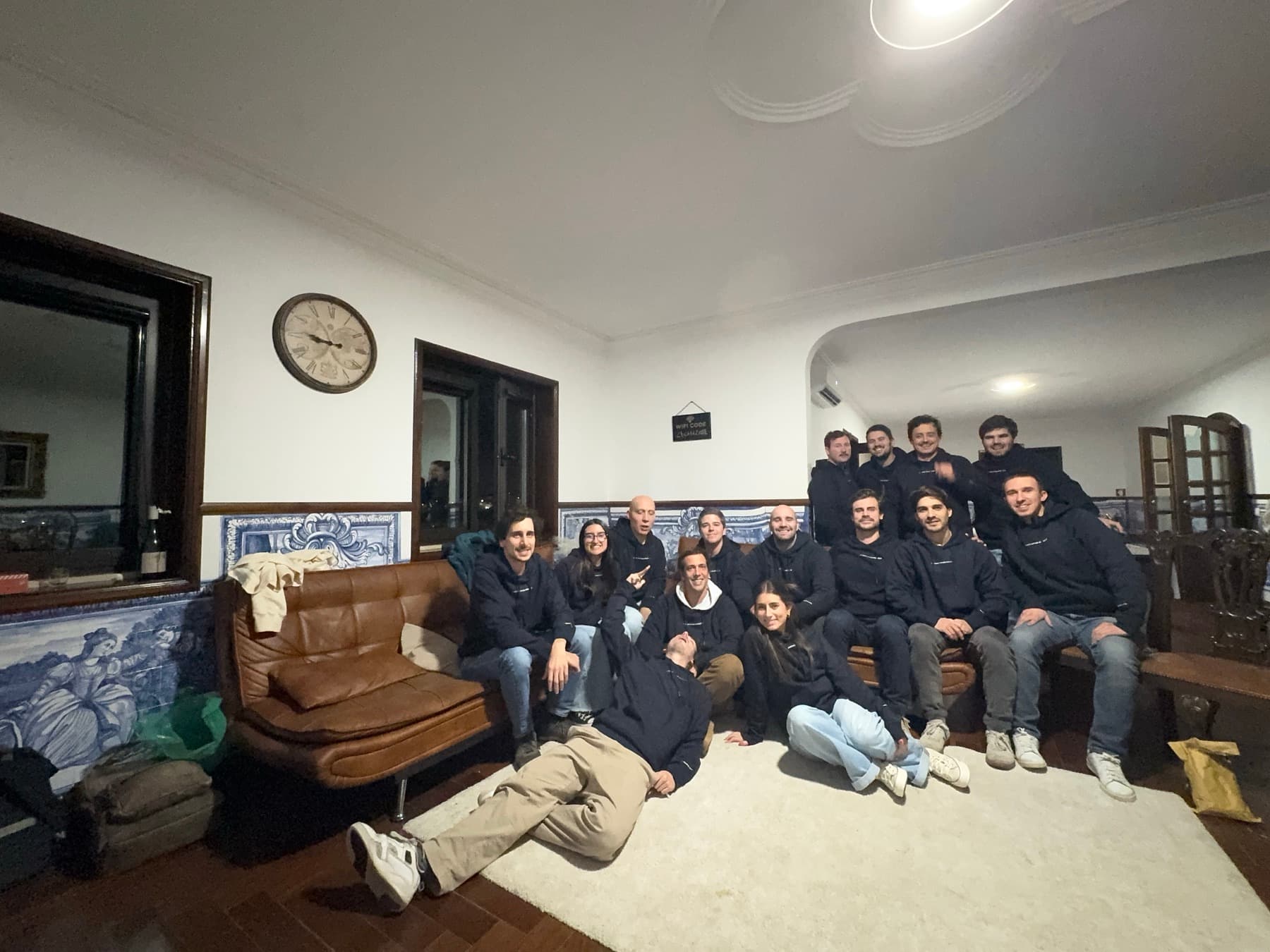 the team squeezed onto a sofa in a tiled living room